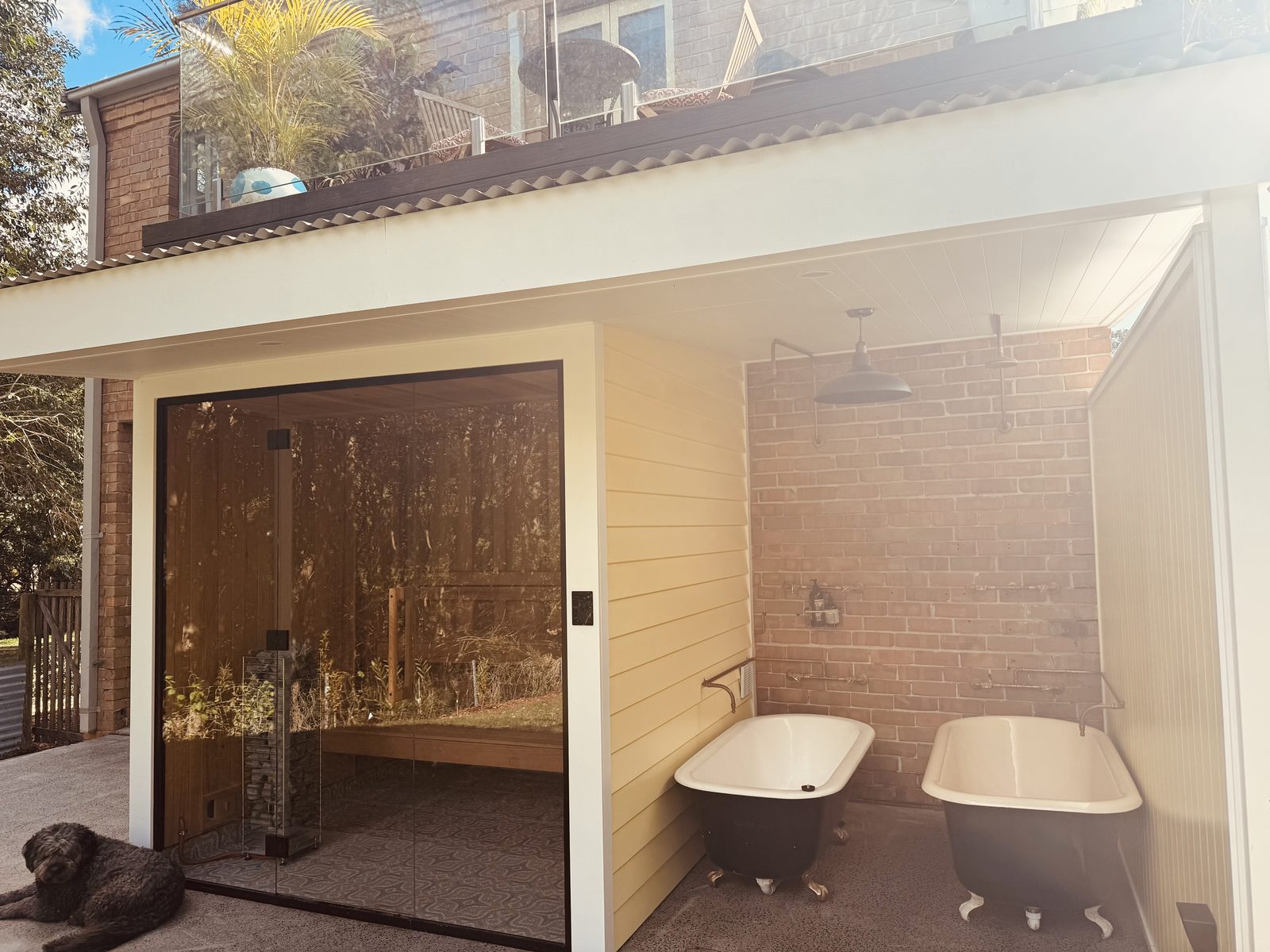 The glass-front sauna and twin clawfoot baths under the deck.